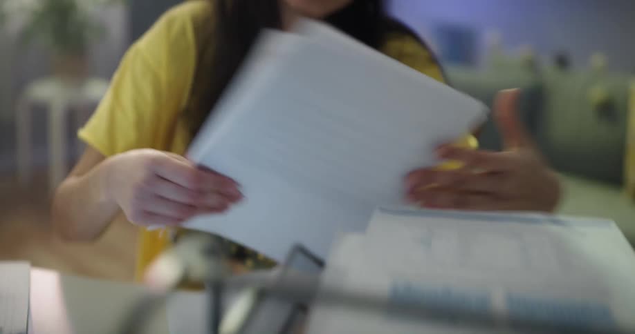 A young woman looks through paper on her desk while studying