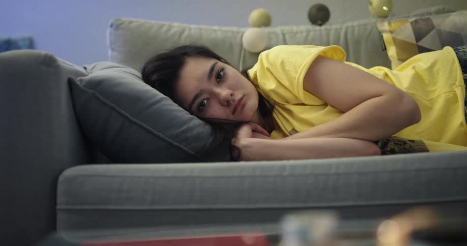 Young asian woman lying on her side in a couch with her head in a cushion