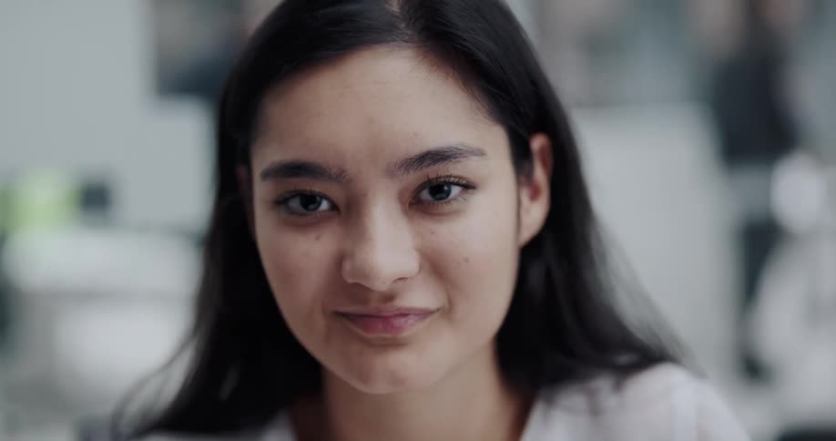 Woman with dark straight hair and white shirt smiles at camera in the office