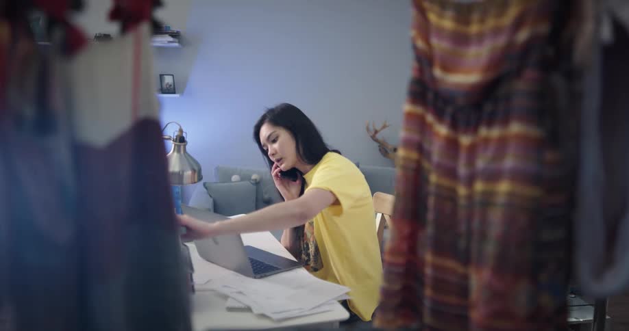 A woman talks on the phone while studying at her desk