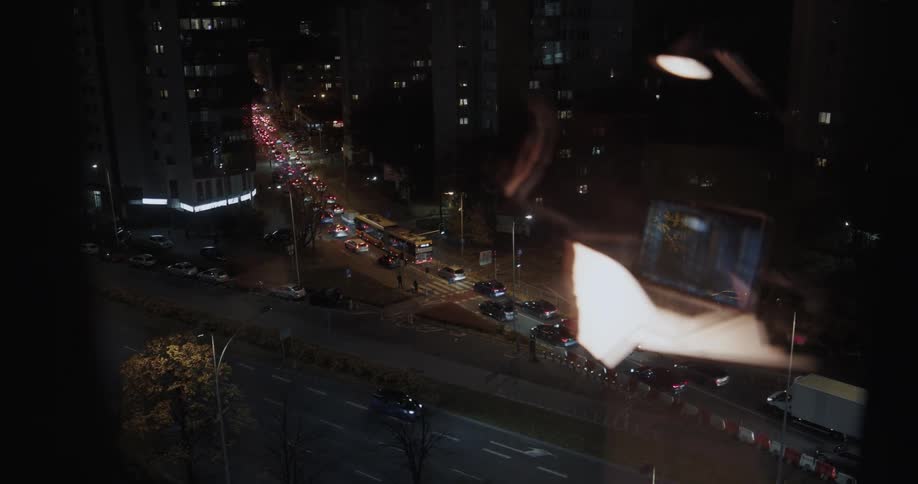 Reflection on a window of a man working late at the office in front of the traffic in the city street