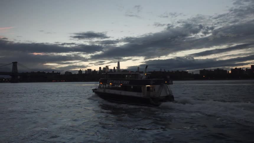 A yacht moves across the water at sunset