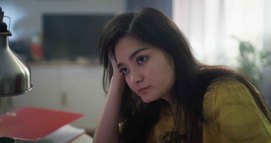 Woman working in office tiredly props head on hand and turns to stare