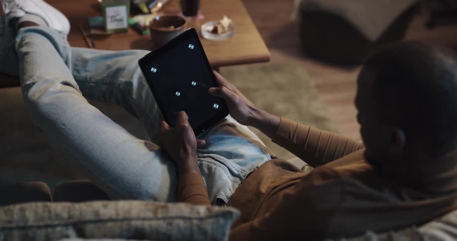 A man is browsing on a tablet indoors