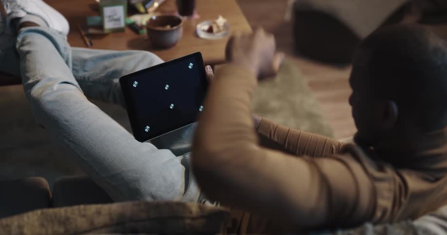 A man uses his tablet while sitting with his legs up on the couch