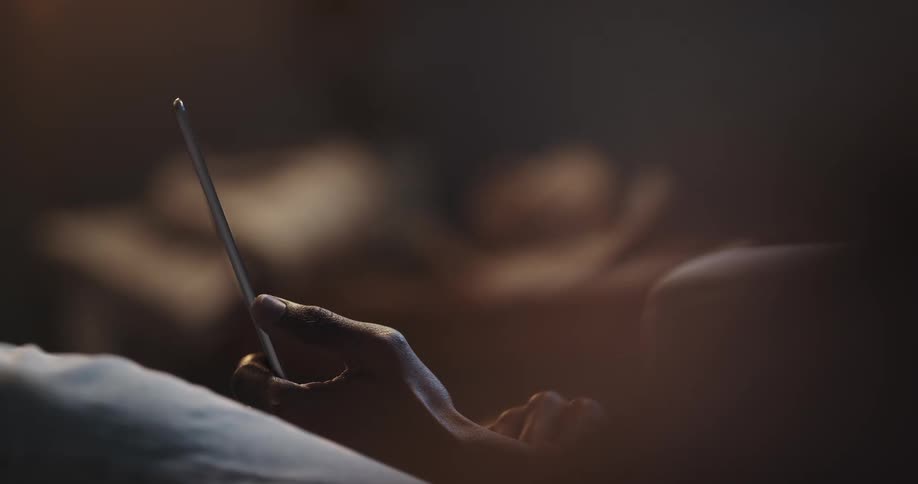 Hand of a man holding his smartphone and scrolling on the screen with his fingers