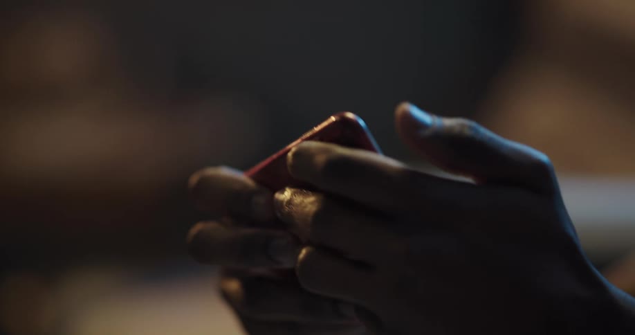 A man turns his phone side to side as he plays on it