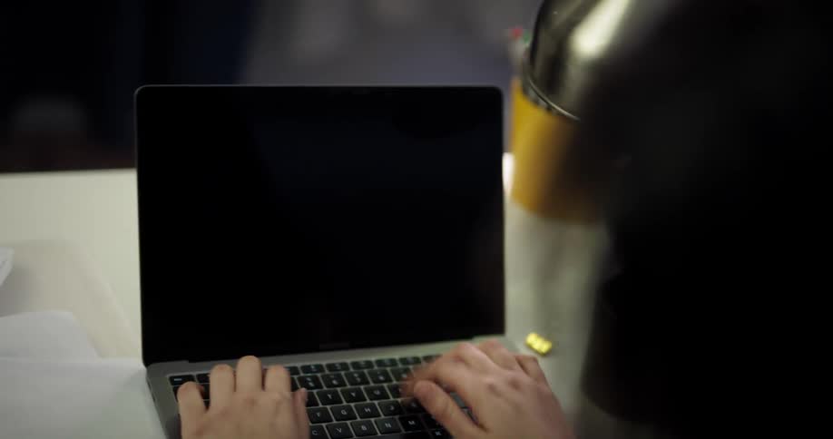 Young woman sitting at a desk at home looks up to think and concentrate before working on a laptop