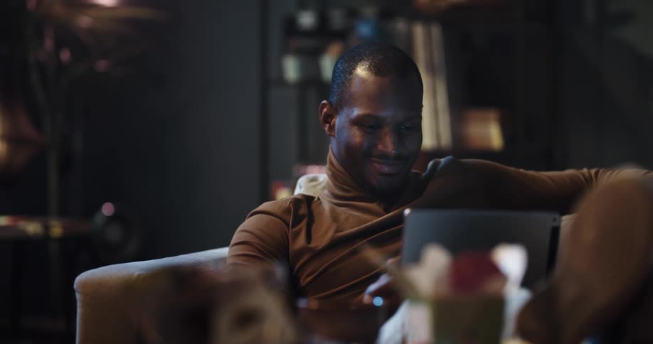 A man is sitting indoors and browsing on a laptop
