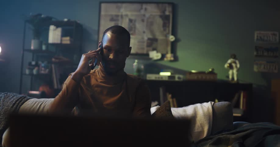 Happy man talks on the phone while sitting on the couch at home