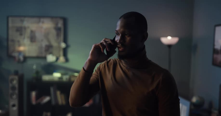 Man talking on his phone at home looks at the screen in confusion