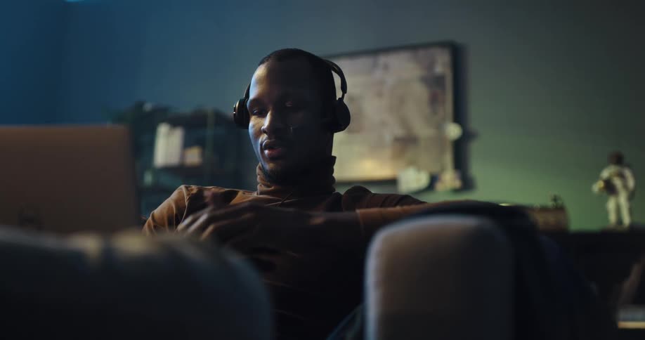 A man talks into a headset while sitting on a sofa in a living room