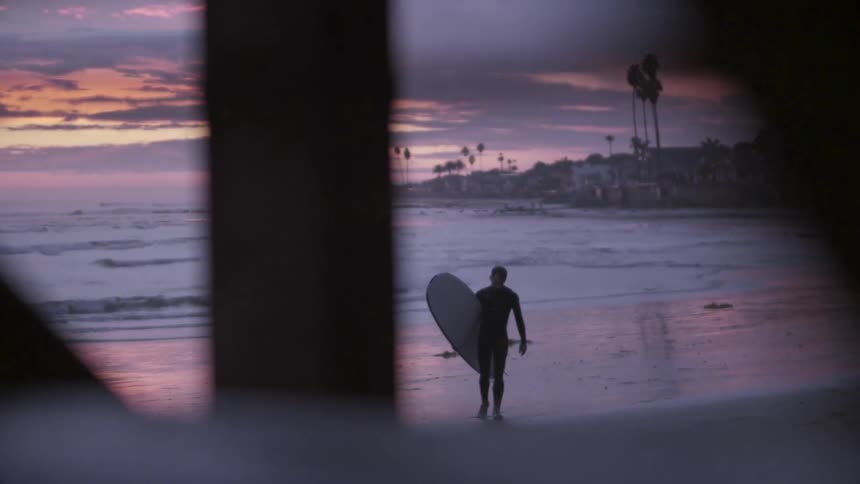 A man walks the beach at sunset
