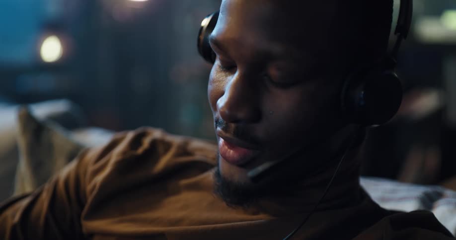 A man wearing a headset smiles and nods while having a conversation