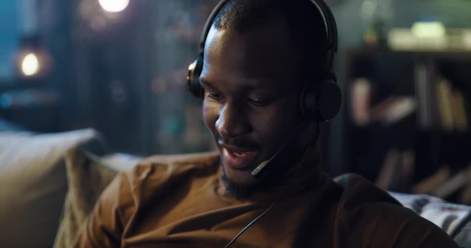 Black man puts on a pair of headphones that have an attached microphone and then smiles and talks