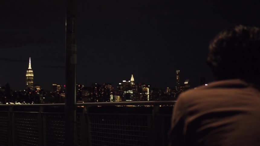 A man gazing at a city skyline at night