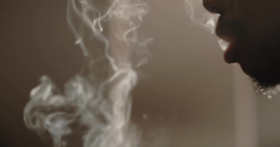 Man with beard smokes weed in living room at home