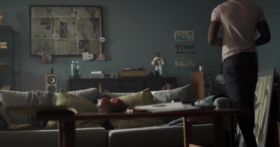 Black man picking a vinyl record putting it on the record player and then putting on a headphone to listen to the music