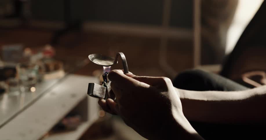 A man holds a flame under drug paraphernalia to heat it up