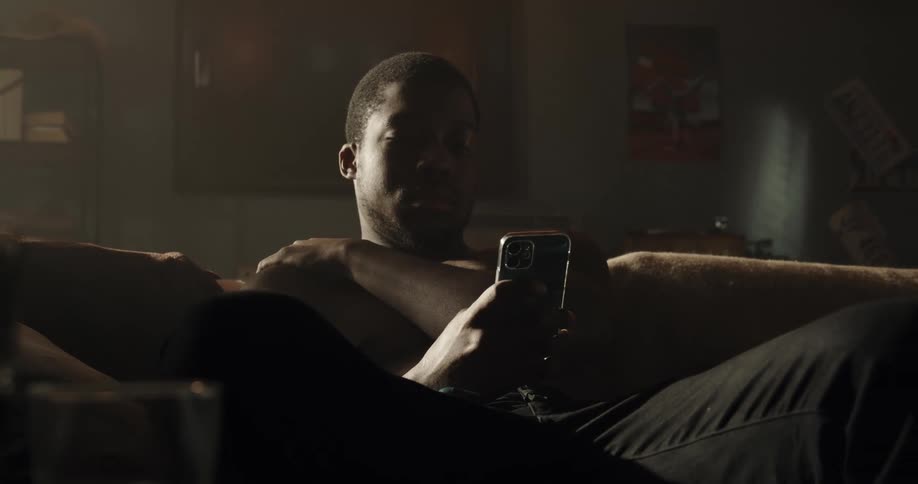 Black man sitting on the couch alone in the living room using his smartphone