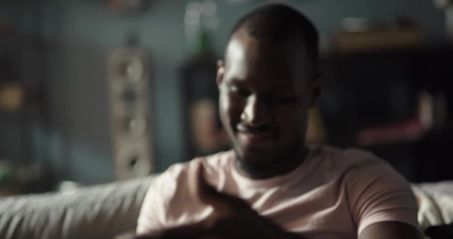 Happy black man sitting on the couch holding a vinyl record