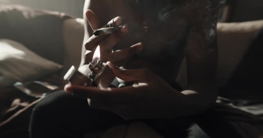 A man uses a lighter to light up a marijuana joint