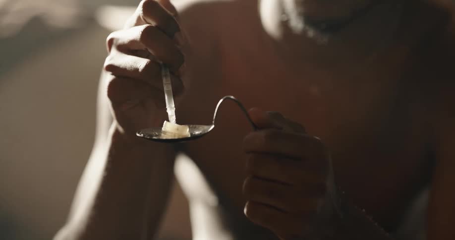 Man uses a syringe to extract liquid from a substance in a spoon