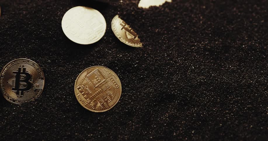 Close up of the shiny engraved surface of golden bitcoin physical coins over dark sand