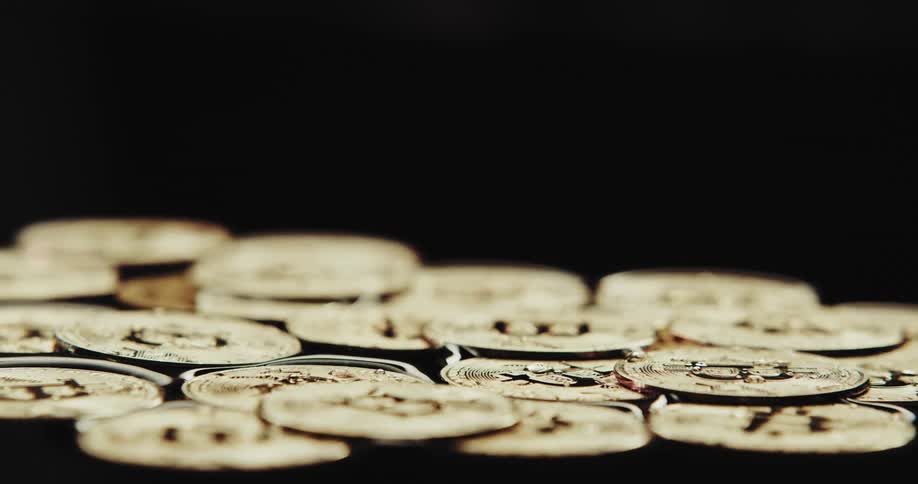 Large round coin spins and falls next to a collection of coins in the water