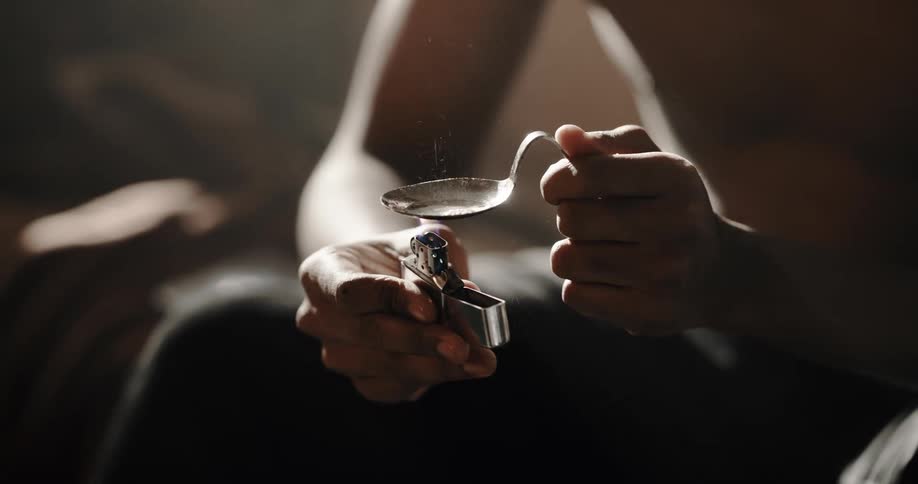 Drug addict heating heroin with a lighter under a metal spoon