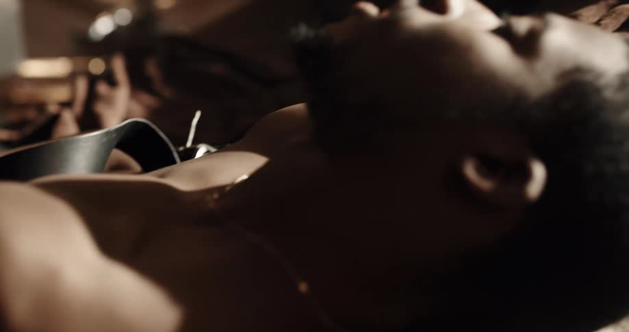 A man lies in bed with a belt strapped around his arm
