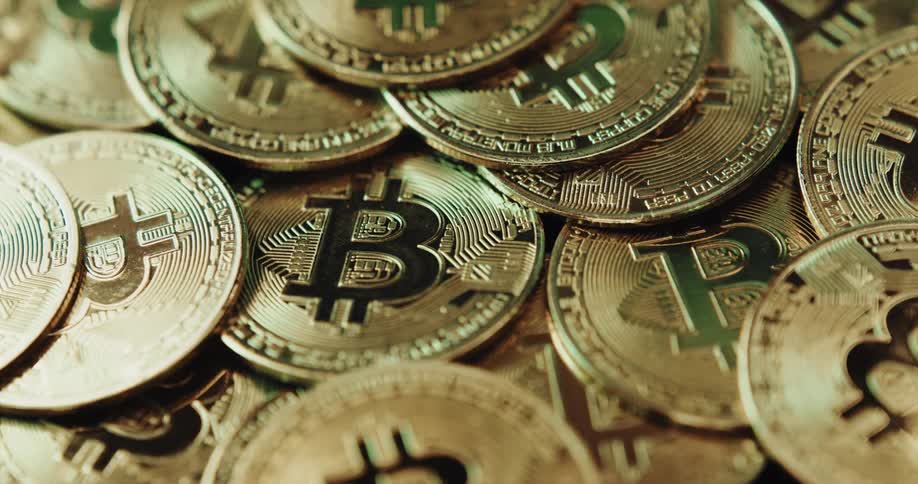 A pile of shiny coins all have the bitcoin cryptocurrency logo on them