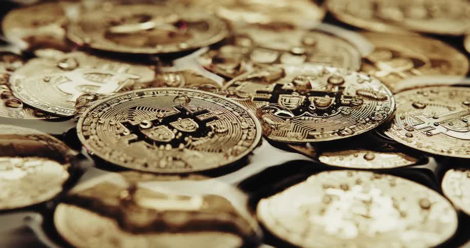 Water falls onto golden coins engraved with bitcoin symbol