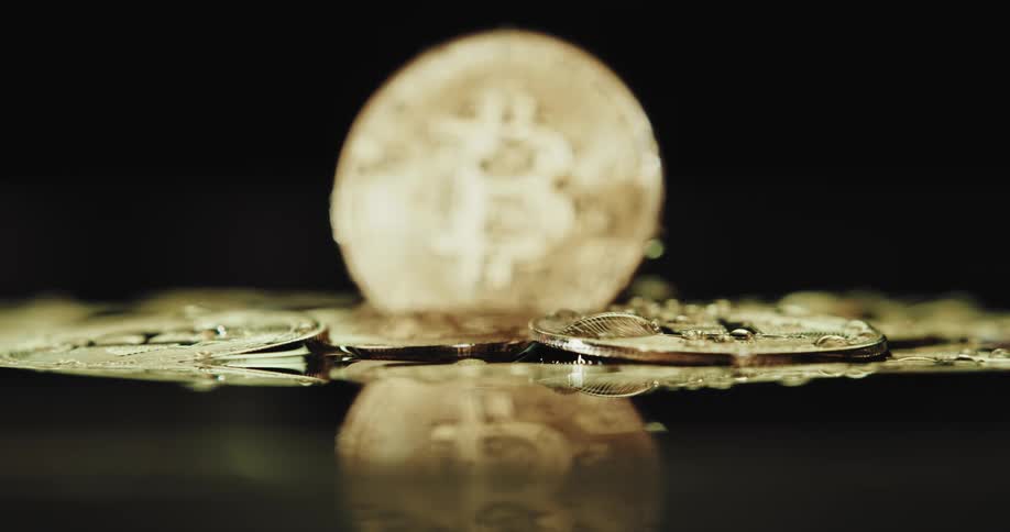 Water droplets cover a pile of gold coins on a table