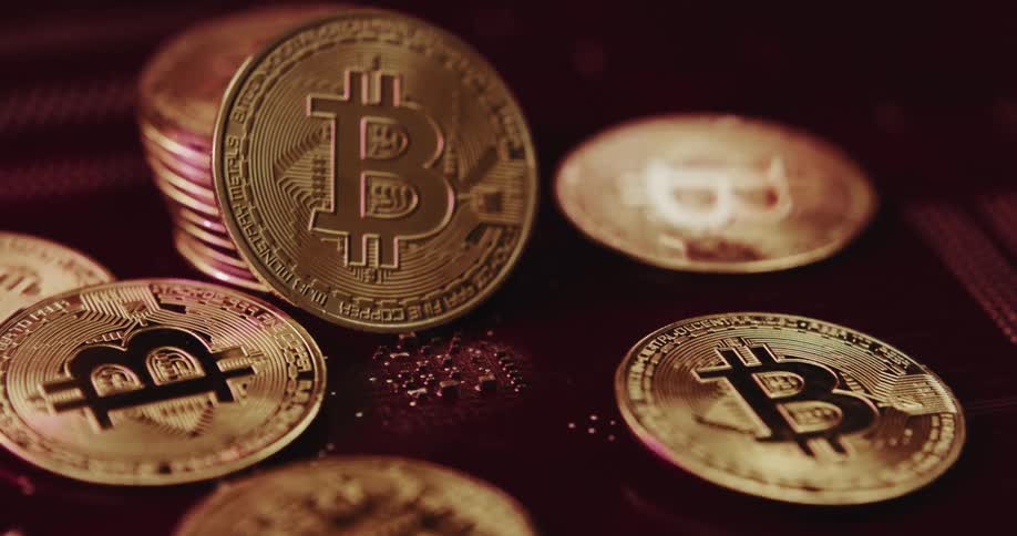 Metallic golden coins with the bitcoin symbol engraved sit on flat surface