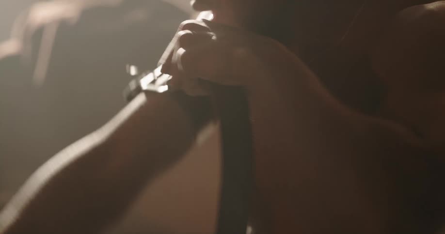 Drug addict tightening belt to his arm before injecting syringe
