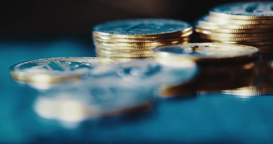 Gold bitcoin coins in small stacks with blue clouds swirling around them