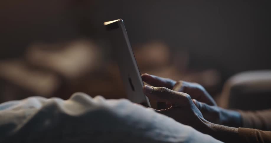 A person holds a tablet computer in their hand while swiping across the screen with their finger