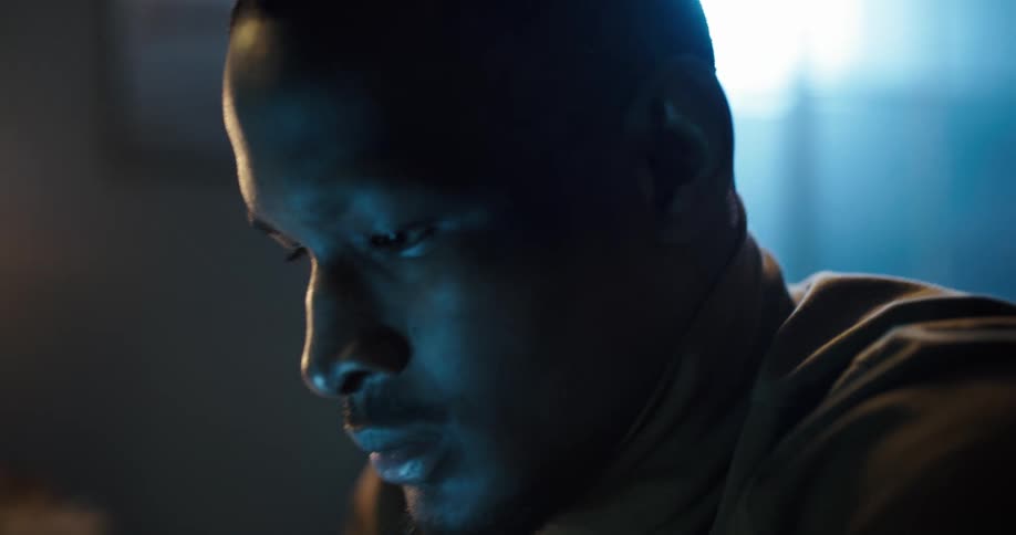 A man sits looking at a screen in disbelief as he shakes his head