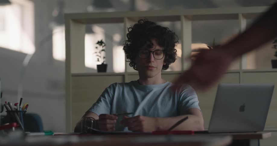 Man sitting at a table looks bored as he moves papers around