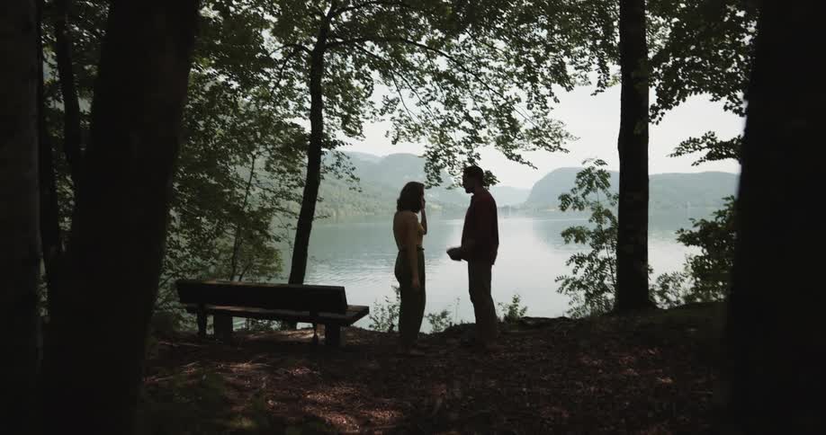 Upset woman pushing and arguing with her boyfriend near a lake outdoors
