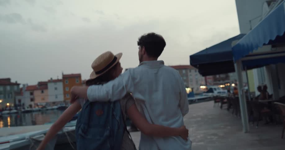 Happy couple holding hands running along the marina while on vacation