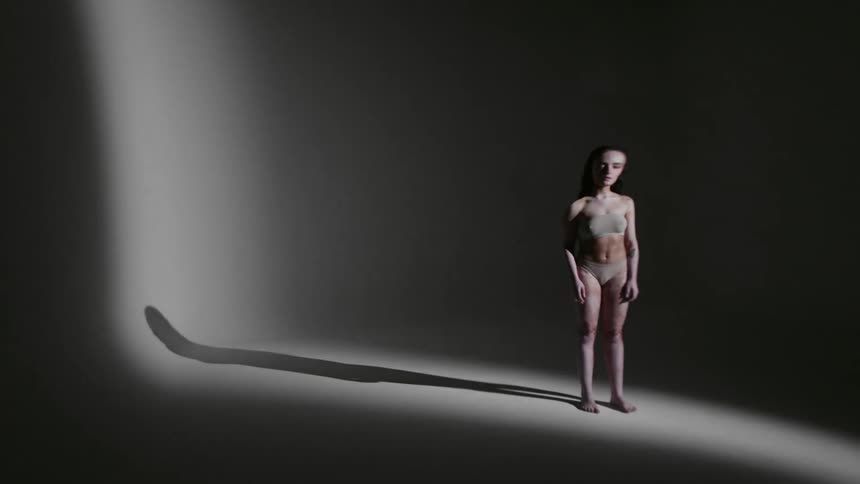 The footage of a female standing in a dark room twists and warps