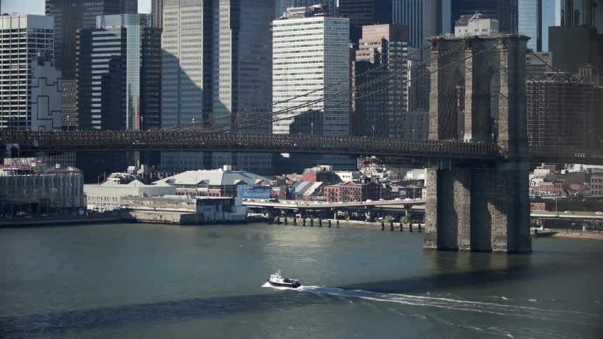 A boat sails under a bridge leading to a city