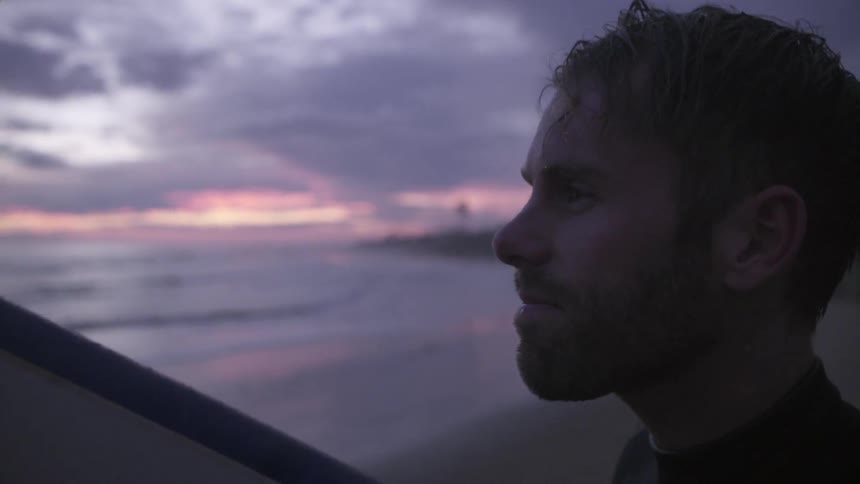 A bearded man looks around a beach