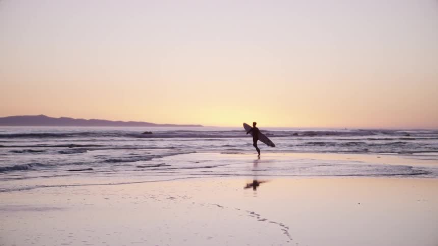 A man runs on the beach at sunset