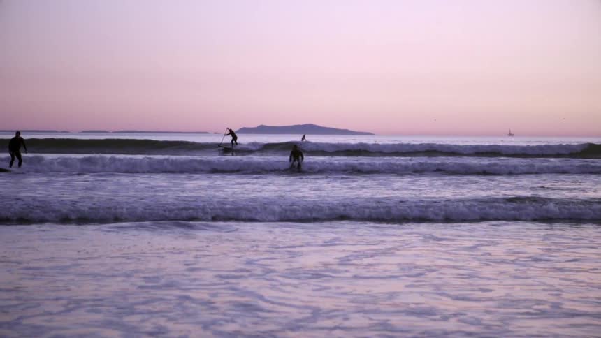 A body of water at sunset with people surfing