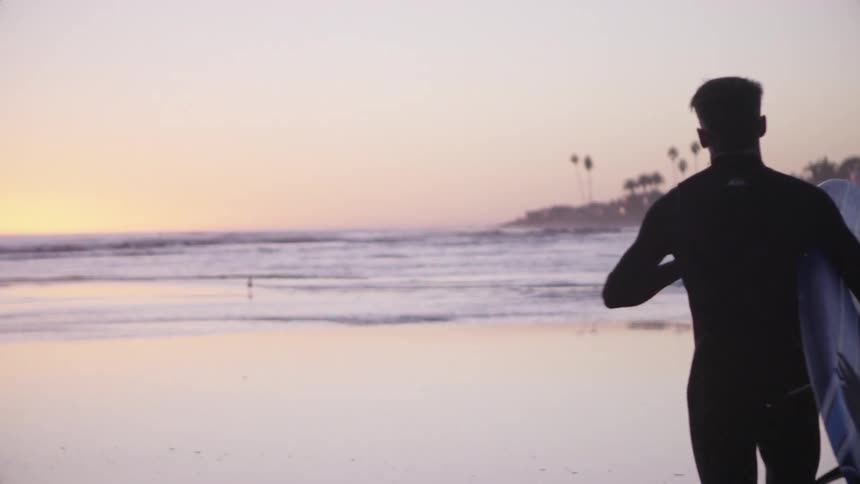 A man is running towards the water with a surfboard