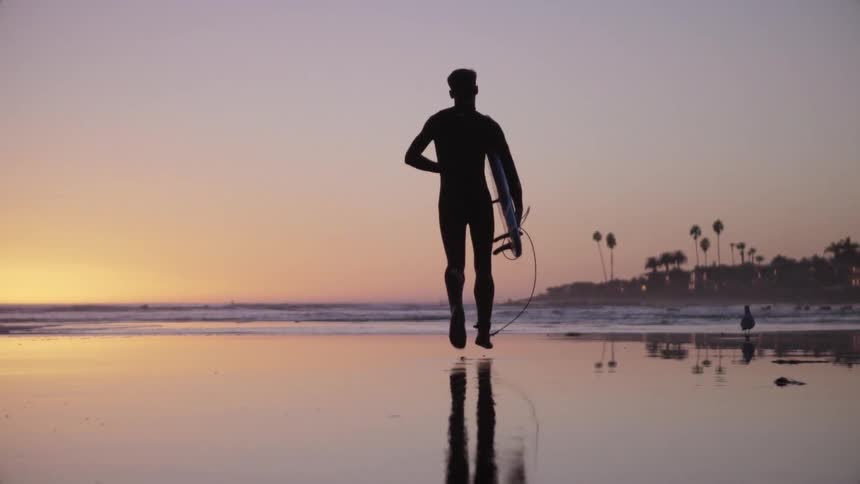 A man runs down the beach at sunset