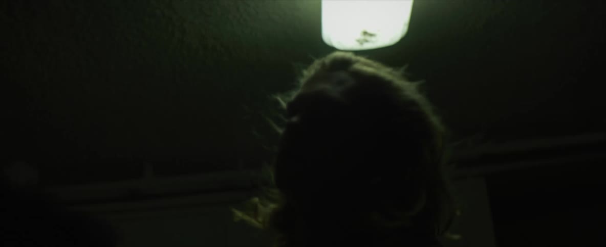 Male biker with long hair and t shirt takes off motorcycle helmet in dark room